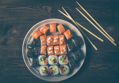 Sushi seti rulo ve sashimi geleneksel yuvarlak tabak içinde görev yaptı. Ahşap arka plan üzerinde sopa ile