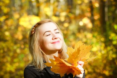 Sonbahar güneşli parkta mutlu genç kadın. Güzel sonbahar günü açık havada gri süveterli neşeli güzel kız.