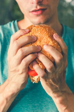 Ahşap arka plan üzerinde erkek elinde sığır eti ile Juisy burger. Gıda kavramı.