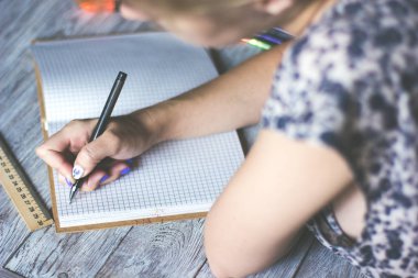 Kadının el ahşap masaüstü çeşitli öğeleri ile yerleştirilen sarmal Defteri'nde yazma yakın çekim