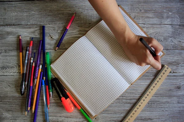 Rechtshänderin hält Stift beim Schreiben auf kleinem Notizbuch auf rostigem Holzboden — Stockfoto