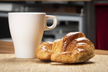 Kruvasan beyaz Kupası ve mutfak arka plan ile