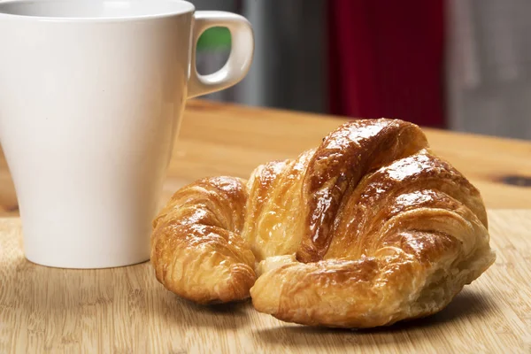 Kruvasan beyaz Kupası ve mutfak arka plan ile