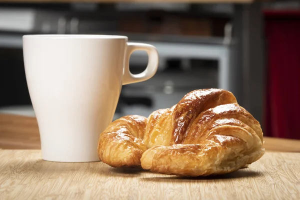 Kruvasan beyaz Kupası ve mutfak arka plan ile