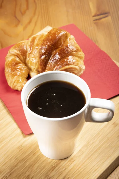 Kırmızı peçete üzerinde kruvasan ile kahve fincan