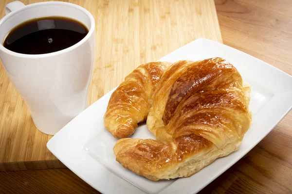 Beyaz tabakta kruvasan ile kahve fincan