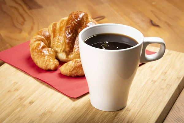 Kırmızı peçete üzerinde kruvasan ile kahve fincan