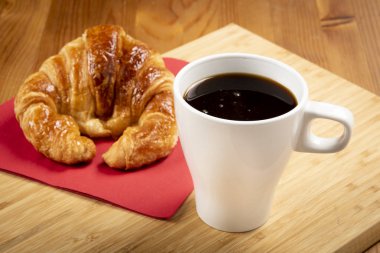 Kırmızı peçete üzerinde kruvasan ile kahve fincan