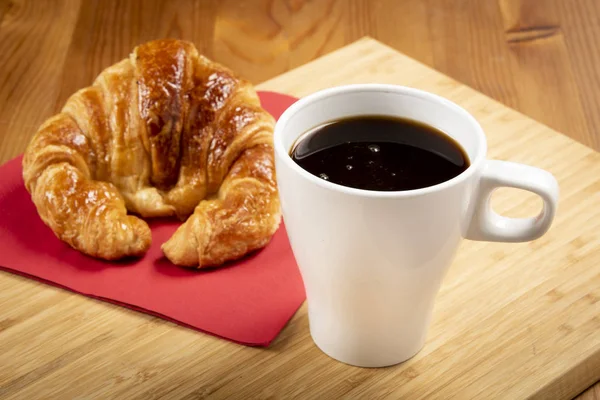 Kırmızı peçete üzerinde kruvasan ile kahve fincan