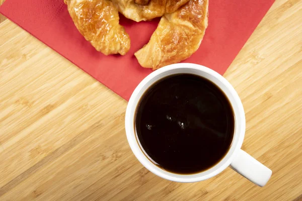 Kırmızı peçete üzerinde kruvasan ile kahve fincan