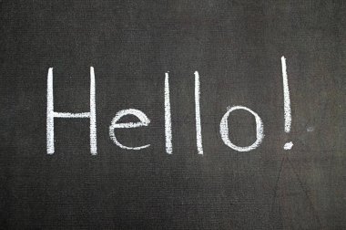 Tebeşirle selamlama. Siyah arkaplanda beyaz metin. Kelime karşılama yatay kavram selam mesajı işareti. Hallo karatahta tasarımını izole etti. Karatahta fotoğraf iletişimi. İngilizce hey konuşma