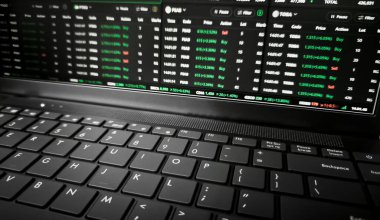 Satın alma ve satma siparişlerini gösteren bulanık borsa ekranlı dizüstü bilgisayarın klavyesini kapat.