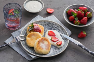 Süzme peynir kahvaltı veya gri arka plan üzerinde öğle yemeği için ekşi krema ve çilek ile krep. Sağlıklı gıda kavramı. Yakın çekim