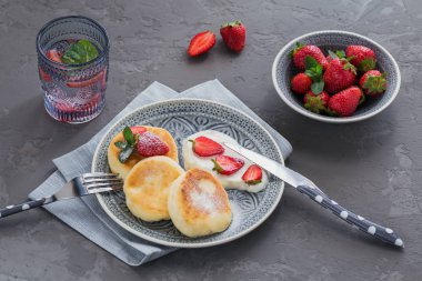 Süzme peynir kahvaltı veya gri arka plan üzerinde öğle yemeği için ekşi krema ve çilek ile krep. Sağlıklı gıda kavramı. Yukarıda