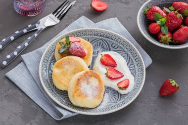 Süzme peynir kahvaltı veya gri arka plan üzerinde öğle yemeği için ekşi krema ve çilek ile krep. Sağlıklı gıda kavramı. Ek yük