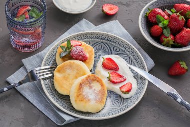 Süzme peynir kahvaltı veya gri arka plan üzerinde öğle yemeği için ekşi krema ve çilek ile krep. Sağlıklı gıda kavramı. Yakın çekim