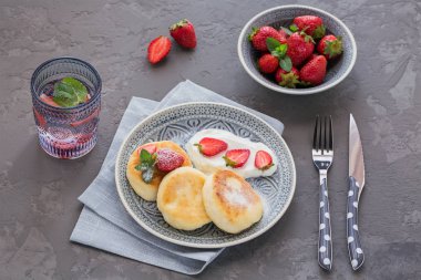 Süzme peynir kahvaltı veya gri arka plan üzerinde öğle yemeği için ekşi krema ve çilek ile krep. Sağlıklı gıda kavramı. Yukarıda