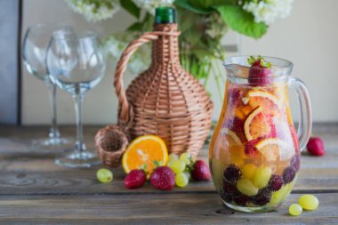 Geleneksel yaz içki beyaz köpüklü şarap sangria. Ev yapımı serinletici meyve sangria veya şampanya, çilek, portakal ve üzüm yumrukla. Bir ahşap rustik masa üzerinde bir sürahi ve malzemeler ile