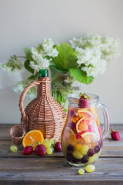Geleneksel yaz içki beyaz köpüklü şarap sangria. Ev yapımı serinletici meyve sangria veya şampanya, çilek, portakal ve üzüm yumrukla. Bir ahşap rustik masa üzerinde bir sürahi ve malzemeler ile
