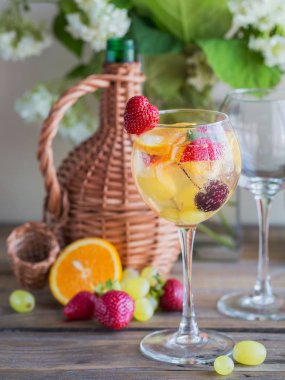 Geleneksel yaz içki beyaz köpüklü şarap sangria. Homemade Meyve sangria şampanya, çilek, portakal ve üzüm ile yenileniyor. Bir sürahi ve malzemeler ile ahşap rustik masaya