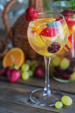 Geleneksel yaz içki beyaz köpüklü şarap sangria. Ev yapımı serinletici meyve sangria veya şampanya, çilek, portakal ve üzüm yumrukla. Yakın çekim