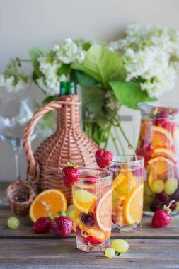 Geleneksel yaz içki beyaz köpüklü şarap sangria. Ev yapımı serinletici meyve sangria veya şampanya, çilek, portakal ve üzüm yumrukla gözlük ve malzemeler ahşap rustik tablo