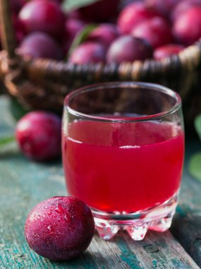 Bir bardak berry içki ve rustik ahşap masa arka plan üzerinde yaprakları ile taze erik. Sonbaharda hasat kavramı. Doğal meyve kompostosu.