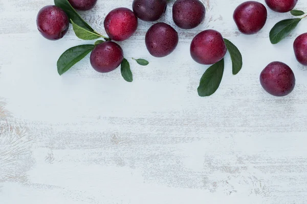 Frische Pflaumen Mit Blättern Auf Weißem Rustikalem Holztischhintergrund Herbsterntekonzept Flache — Stockfoto