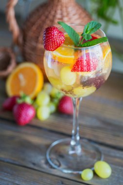 Geleneksel yaz içki beyaz köpüklü şarap sangria. Ev yapımı serinletici meyve sangria veya şampanya, çilek, portakal ve üzüm yumrukla gözlük ve malzemeler ahşap rustik tablo