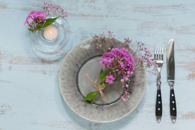 Pembe çiçek ve mum Işık ahşap masa üzerinde rustik tablo ayarı. Tatil dekorasyon Provence stili. Romantik bir akşam yemeği. Düz metin için kopya yer ile göklere