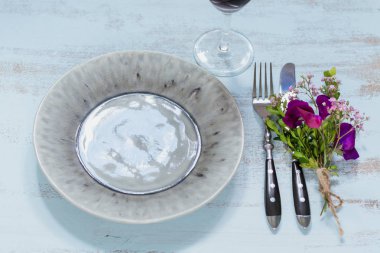 Rustik sofra mor çiçekler ve hafif ahşap masa üzerinde kırmızı şarap ile. Tatil dekorasyon Provence stili. Romantik bir akşam yemeği. Üstten görünüm