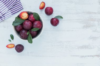 Taze erik kase yapraklarda beyaz rustik ahşap masa arka plan ile. Sonbaharda hasat kavramı. Metin kopyalama yeri olan üstten görünüm