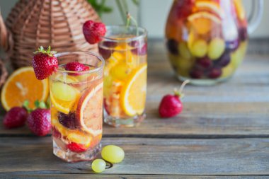 Geleneksel yaz içki beyaz köpüklü şarap sangria. Ev yapımı serinletici meyve sangria veya şampanya, çilek, portakal ve üzüm yumrukla gözlük ve malzemeler ahşap rustik tablo