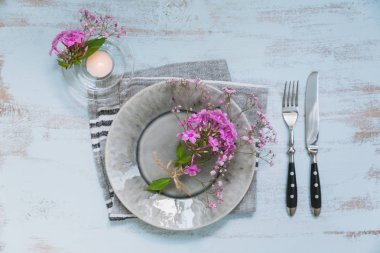 Pembe çiçek ve mum Işık ahşap masa üzerinde rustik tablo ayarı. Tatil dekorasyon Provence stili. Romantik bir akşam yemeği. Ek yük