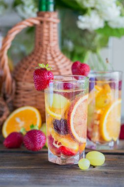 Geleneksel yaz içki beyaz köpüklü şarap sangria. Ev yapımı serinletici meyve sangria veya şampanya, çilek, portakal ve üzüm yumrukla gözlük ve malzemeler ahşap rustik tablo