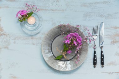 Pembe çiçek ve mum Işık ahşap masa üzerinde rustik tablo ayarı. Tatil dekorasyon Provence stili. Romantik bir akşam yemeği. Üstten görünüm 