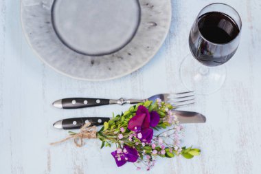 Rustik sofra mor çiçekler ve hafif ahşap masa üzerinde kırmızı şarap ile. Tatil dekorasyon Provence stili. Romantik bir akşam yemeği. Üstten görünüm 