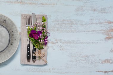 Rustik tablo ayarı ile ışık ahşap masa üzerinde mor çiçekler. Tatil dekorasyon Provence stili. Romantik bir akşam yemeği. Metin kopyalama yeri olan üstten görünüm