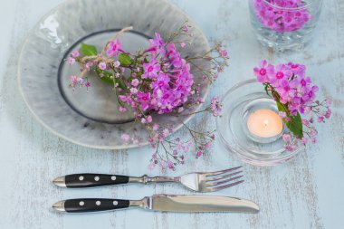 Pembe çiçek ve mum Işık ahşap masa üzerinde rustik tablo ayarı. Tatil dekorasyon Provence stili. Romantik bir akşam yemeği. Ek yük