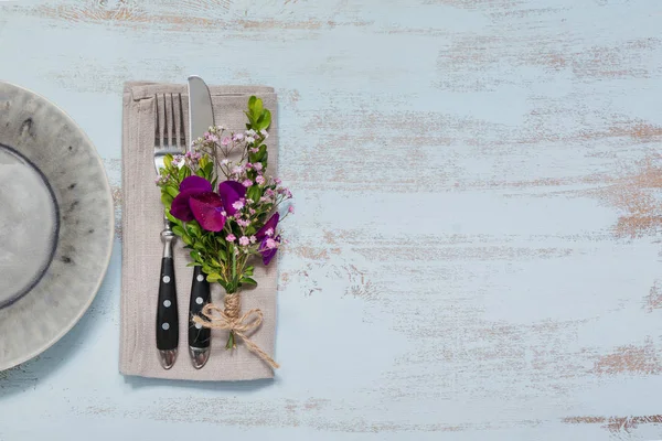 Rustik tablo ayarı ile ışık ahşap masa üzerinde mor çiçekler. Tatil dekorasyon Provence stili. Romantik bir akşam yemeği. Metin kopyalama yeri olan üstten görünüm