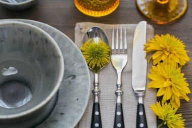 Rustik sofra keten peçete, çatal bıçak takımları, seramik kaplamalar, sarı gözlük ve koyu ahşap masaya sarı çiçek. Tatil masa dekorasyonu. Romantik bir akşam yemeği.