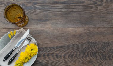 Rustik sofra keten peçete, çatal bıçak takımları, seramik kaplamalar, sarı gözlük ve koyu ahşap masaya sarı çiçek. Tatil masa dekorasyonu. Romantik bir akşam yemeği.