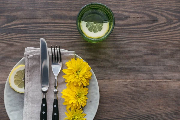 Rustik sofra keten peçete, çatal bıçak takımları, seramik kaplamalar, sarı gözlük ve koyu ahşap masaya sarı çiçek. Tatil masa dekorasyonu. Romantik bir akşam yemeği.