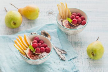 Taze meyve, chia tohum, ahududu ve sağlıklı vegan vejetaryen diyet kahvaltı için beyaz rustik ahşap arka plan üzerinde incir ile güler yüzlü kase. Sağlıklı gıda kavramı