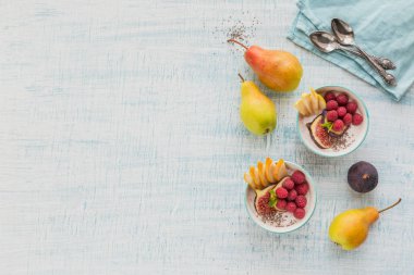 Taze meyve, chia tohum, ahududu ve sağlıklı vegan vejetaryen diyet kahvaltı için beyaz rustik ahşap arka plan üzerinde incir ile güler yüzlü kase. Sağlıklı gıda kavramı. Üstten görünüm