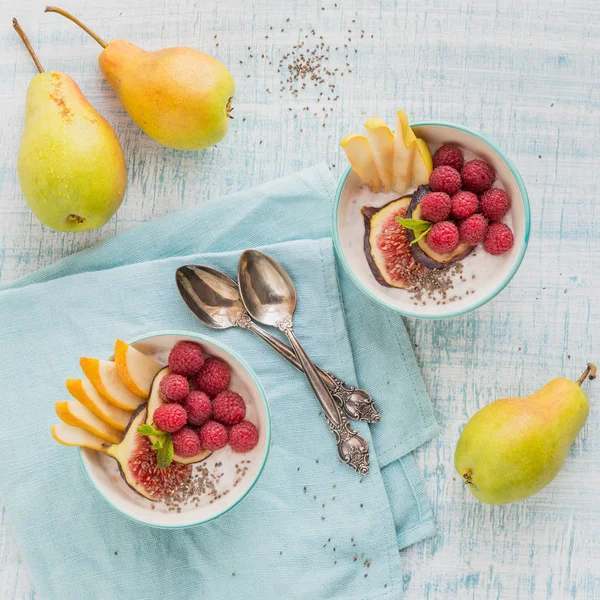 Taze meyve, chia tohum, ahududu ve sağlıklı vegan vejetaryen diyet kahvaltı için beyaz rustik ahşap arka plan üzerinde incir ile güler yüzlü kase. Sağlıklı gıda kavramı. Düz yatıyordu