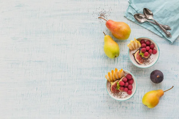 Taze meyve, chia tohum, ahududu ve sağlıklı vegan vejetaryen diyet kahvaltı için beyaz rustik ahşap arka plan üzerinde incir ile güler yüzlü kase. Sağlıklı gıda kavramı. Üstten görünüm