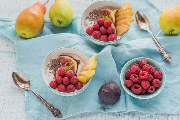 Taze meyve, chia tohum, ahududu ve sağlıklı vegan vejetaryen diyet kahvaltı için beyaz rustik ahşap arka plan üzerinde incir ile güler yüzlü kase. Sağlıklı gıda kavramı. Üstten görünüm