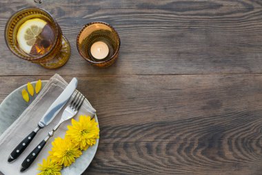 Rustik tablo ayarını keten peçete, çatal bıçak takımları, seramik kaplamalar, sarı gözlük ve sarı çiçek