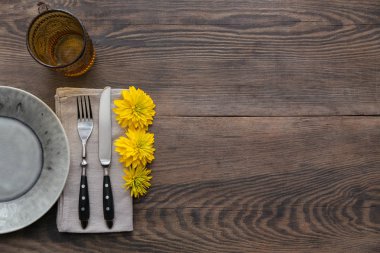 Rustik tablo ayarını keten peçete, çatal bıçak takımları, seramik kaplamalar, sarı gözlük ve sarı çiçek